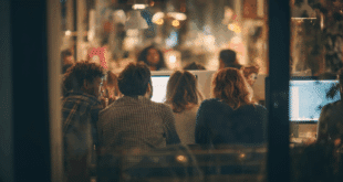 Groupe de travail en coworking rassemblé autour d’un ordinateur, dans une ambiance tech à la fois sérieuse et conviviale.