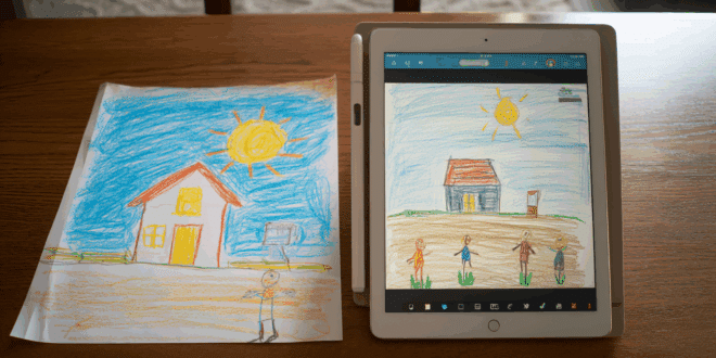 Un dessin d’enfant très simple (maison, soleil, bonhommes bâtons) posé sur une table, à côté d’une tablette ou d’un écran affichant la version œuvre d’art du même dessin