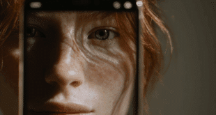 Un visage humain (ni très beau ni très laid, volontairement neutre) regarde un écran de smartphone affichant l’interface de ChatGPT.