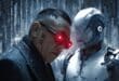 Un chinois du genre mafieux avec lunette rouge devant un robot