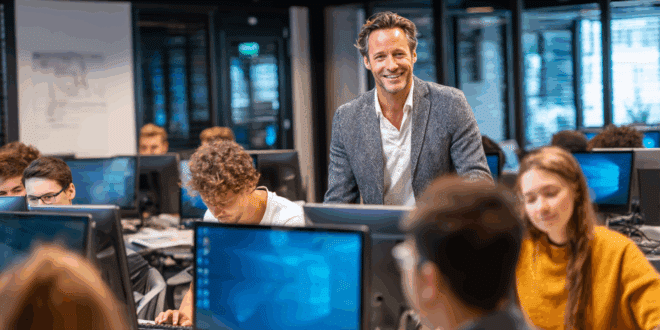 Un jeune formateur souriant, portant une tenue semi-formelle décontractée, se tient devant une salle de formation moderne.