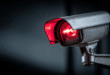 Une webcam allumée, avec une lumière rouge symbolisant la surveillance