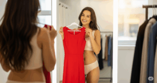 Une femme en train d'essayer une robe rouge devant un miroir