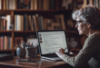 Une écrivaine travaillant sur un document .docx sur son ordinateur portable, entourée de livres, illustrant la création de contenu