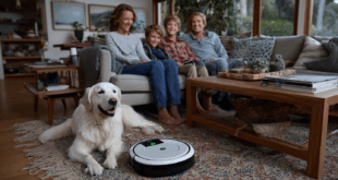 famille assise avec sérénité et joie sur un canapé et devant se trouve un aspirateur robot