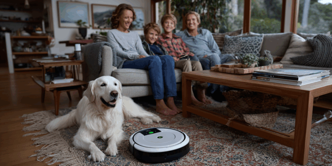famille assise avec sérénité et joie sur un canapé et devant se trouve un aspirateur robot