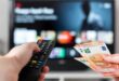 Une main tenant une télécommande et une autre tenant une ammende, IPTV