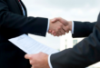 deux homme en costume passant un accord, papier à lamain de l'un