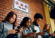 élèves dos à un mur affichant interdiction de réseaux sociaux aux mineurs