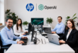 Des employés utilisent des ordinateurs HP dans un bureau moderne, avec les logos HP, OpenAI et Frontier en arrière-plan.