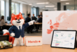 Renard mascotte de Mendo en costume d’affaires devant une carte de l’Europe et un tableau de bord IA, avec une mallette remplie d’euros dans un bureau moderne.