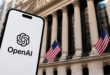 Logo OpenAI affiché sur un smartphone devant un bâtiment financier américain.