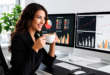 Femme professionnelle souriante buvant un café à son bureau, devant deux écrans affichant des graphiques SEO.