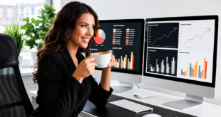 Femme professionnelle souriante buvant un café à son bureau, devant deux écrans affichant des graphiques SEO.